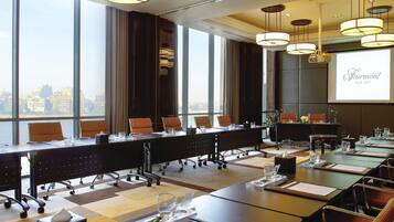 Et mødelokale med et langt bord, stole og et projektorskærm der viser 'Fairmont Nile City'.