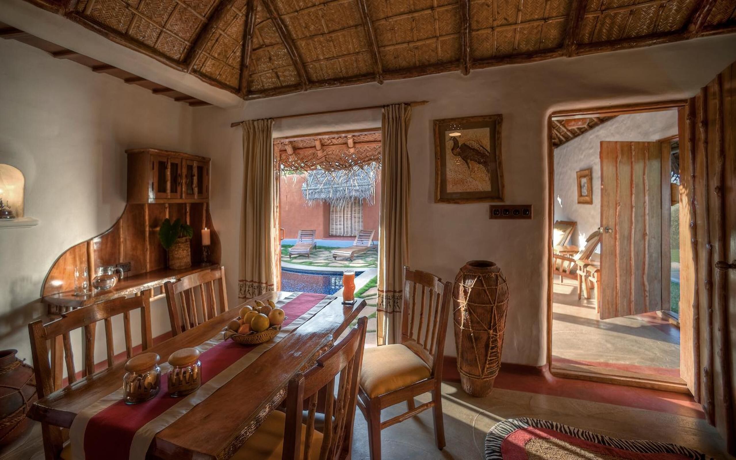 Un espace repas avec une table en bois, des chaises et un buffet. On peut admirer une piscine et un coin salon extérieur.