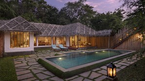 A poolside area with a thatched-roof structure, lounge chairs, and a well-maintained lawn. - Evolve Back, Kabini (Heggadadevankote)
