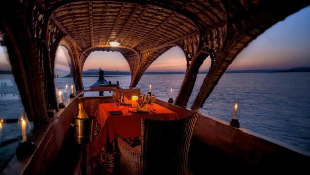 A dining area with a table set for two, overlooking a body of water at sunset. - Evolve Back, Kabini (Heggadadevankote)