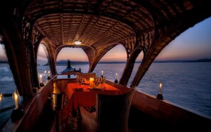 A dining area with a table set for two, overlooking a body of water at sunset. - Evolve Back, Kabini (Heggadadevankote)