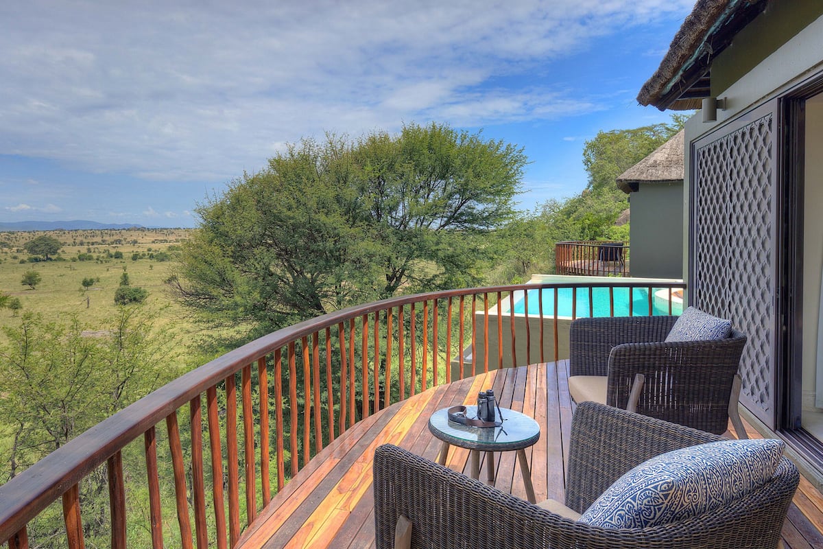Ein Balkon mit Korbmöbeln, einem Pool und Blick auf die Landschaft.