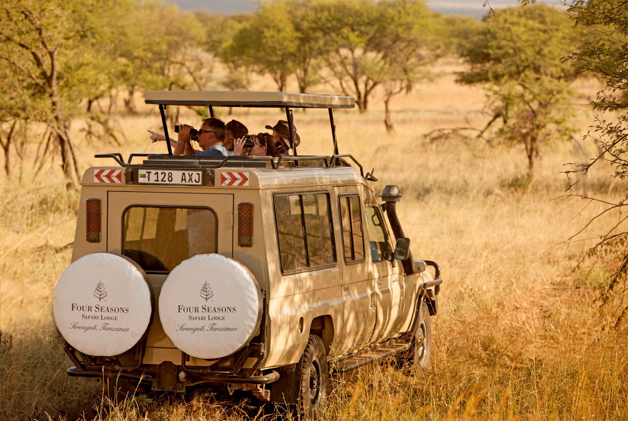 A safari vehicle with two spare tires labeled "Four Seasons Safari Lodge" and "Serongeti, Tanzania" on the back.
