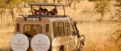 A safari vehicle with two spare tires labeled "Four Seasons Safari Lodge" and "Serongeti, Tanzania" on the back.
