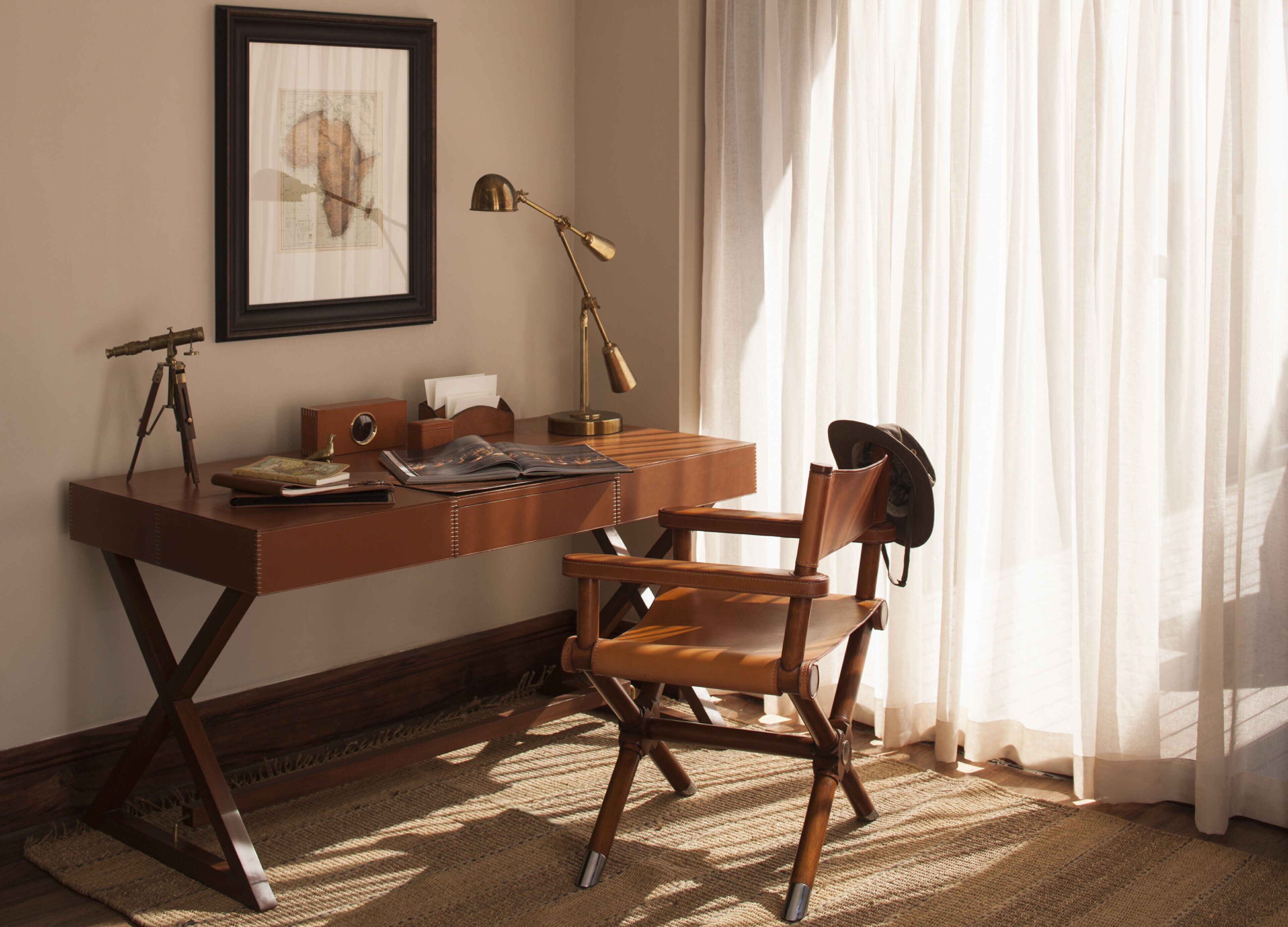A study with a desk, chair, lamp, and a framed picture on the wall.