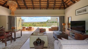 A spacious living room with a large TV, comfortable seating, and a view of the countryside.