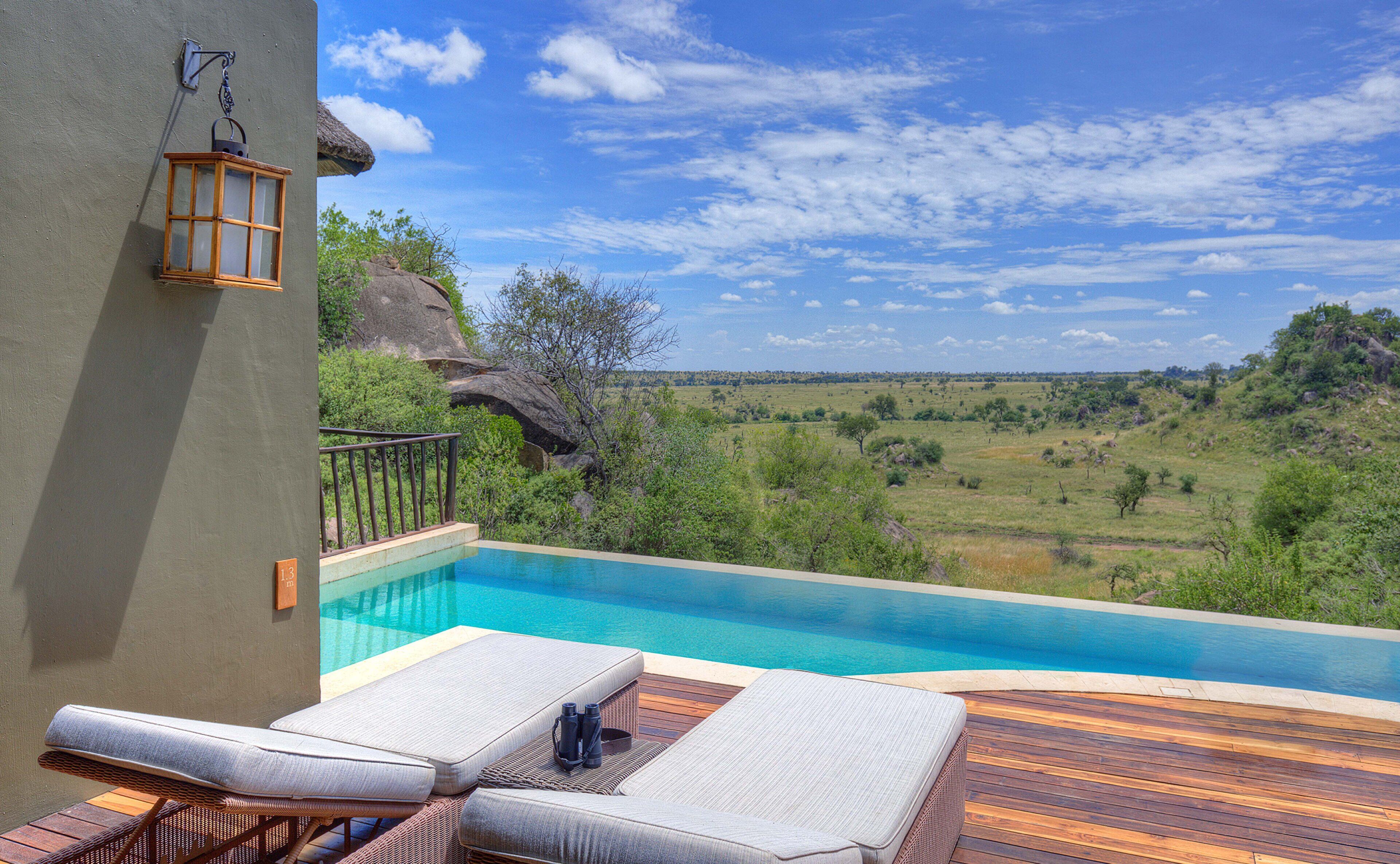 Área da piscina com espreguiçadeiras e vista para uma paisagem natural.