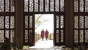 A wooden walkway leading to a traditional gate with intricate lattice designs.