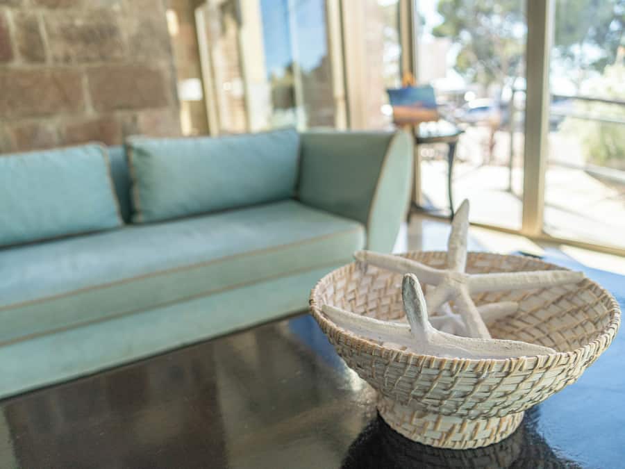 A wicker bowl on a table with a light blue sofa in the background.