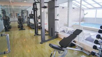 A gym with cardio machines, weightlifting equipment, and a bench.