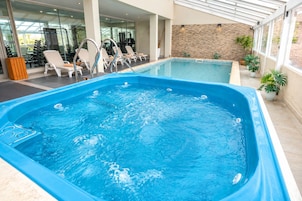 Una piscina con hidromasaje, rodeada de sillones de descanso y equipo de ejercicio.