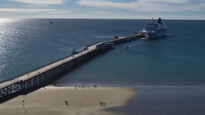 Un muelle se adentra en aguas tranquilas, con un crucero atracado al final.