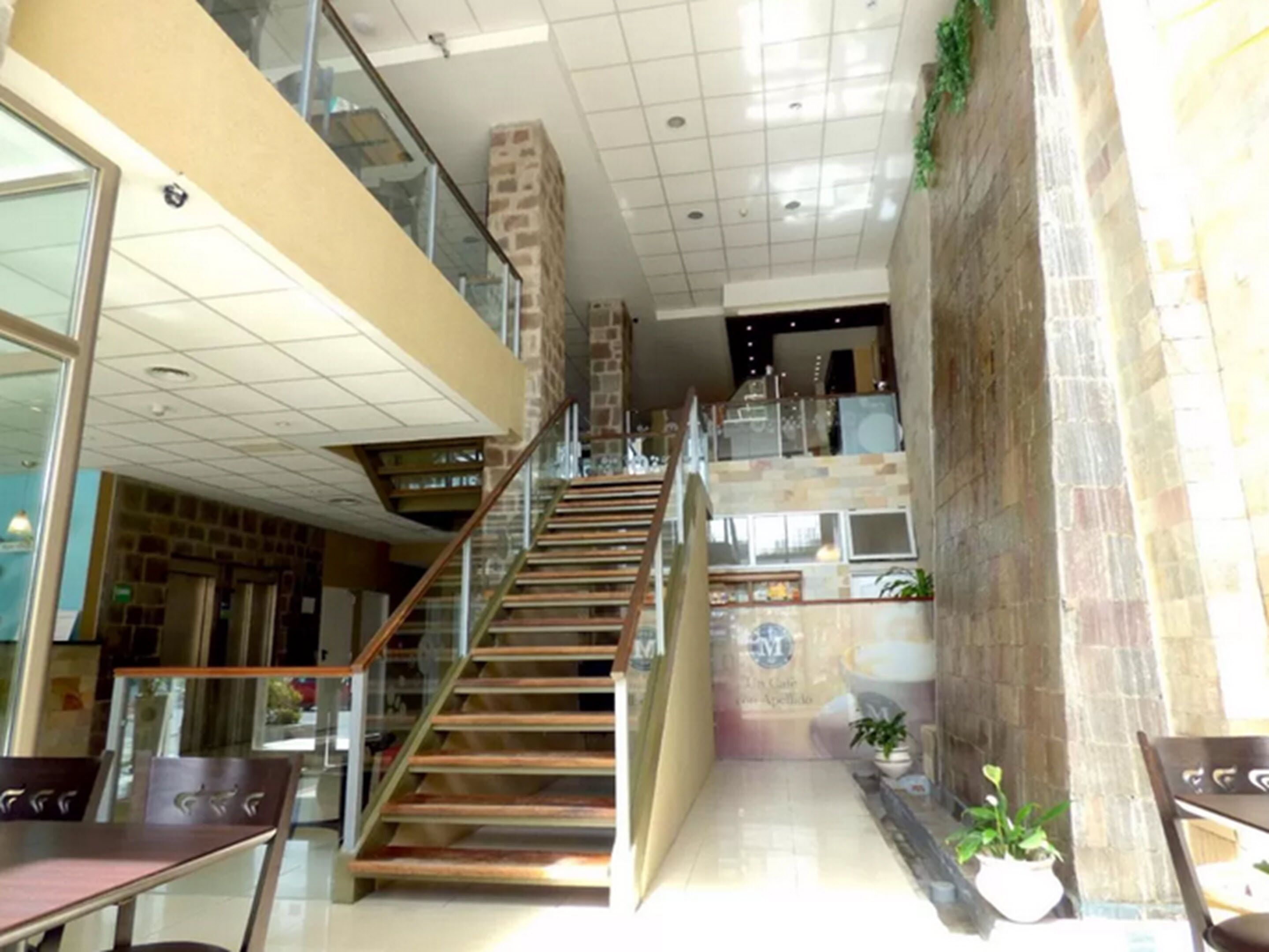 A multi-level interior with a staircase, glass railings, and a mix of stone and tiled flooring.
