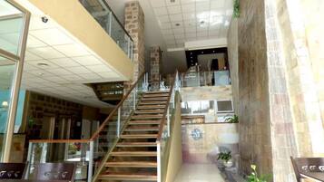 A multi-level interior with a staircase, glass railings, and a mix of stone and tiled flooring.