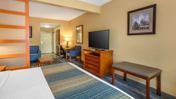 A hotel room with a bed, a desk, a chair, a television, and a framed picture on the wall.