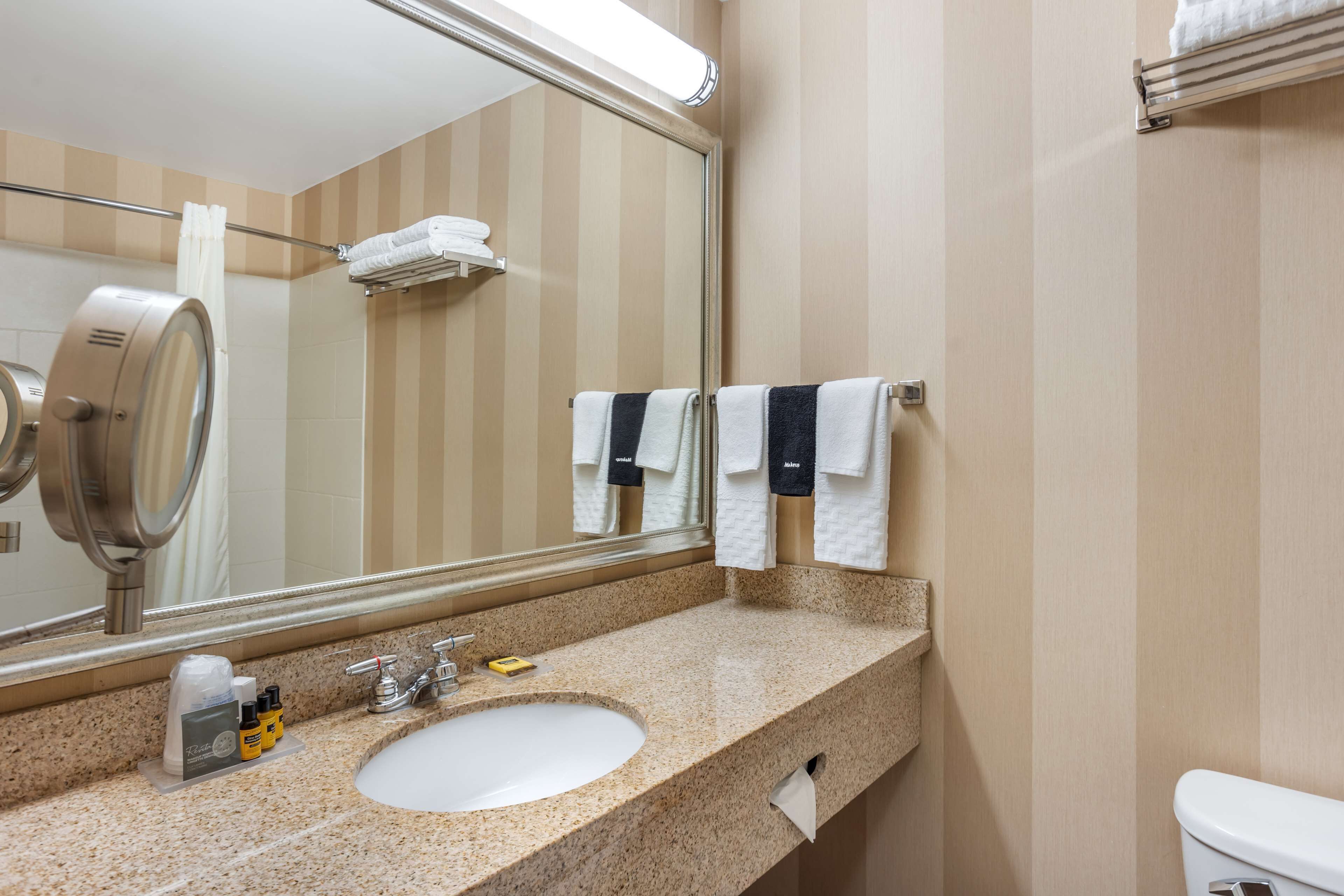 A bathroom with a sink, mirror, towel rack, and toilet.