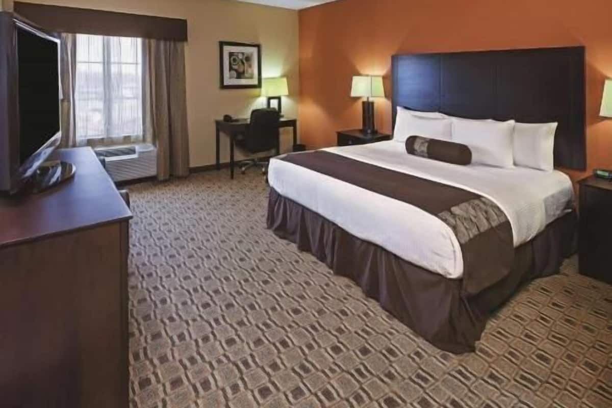 A hotel room with a bed, a desk, a television, and a window with curtains.