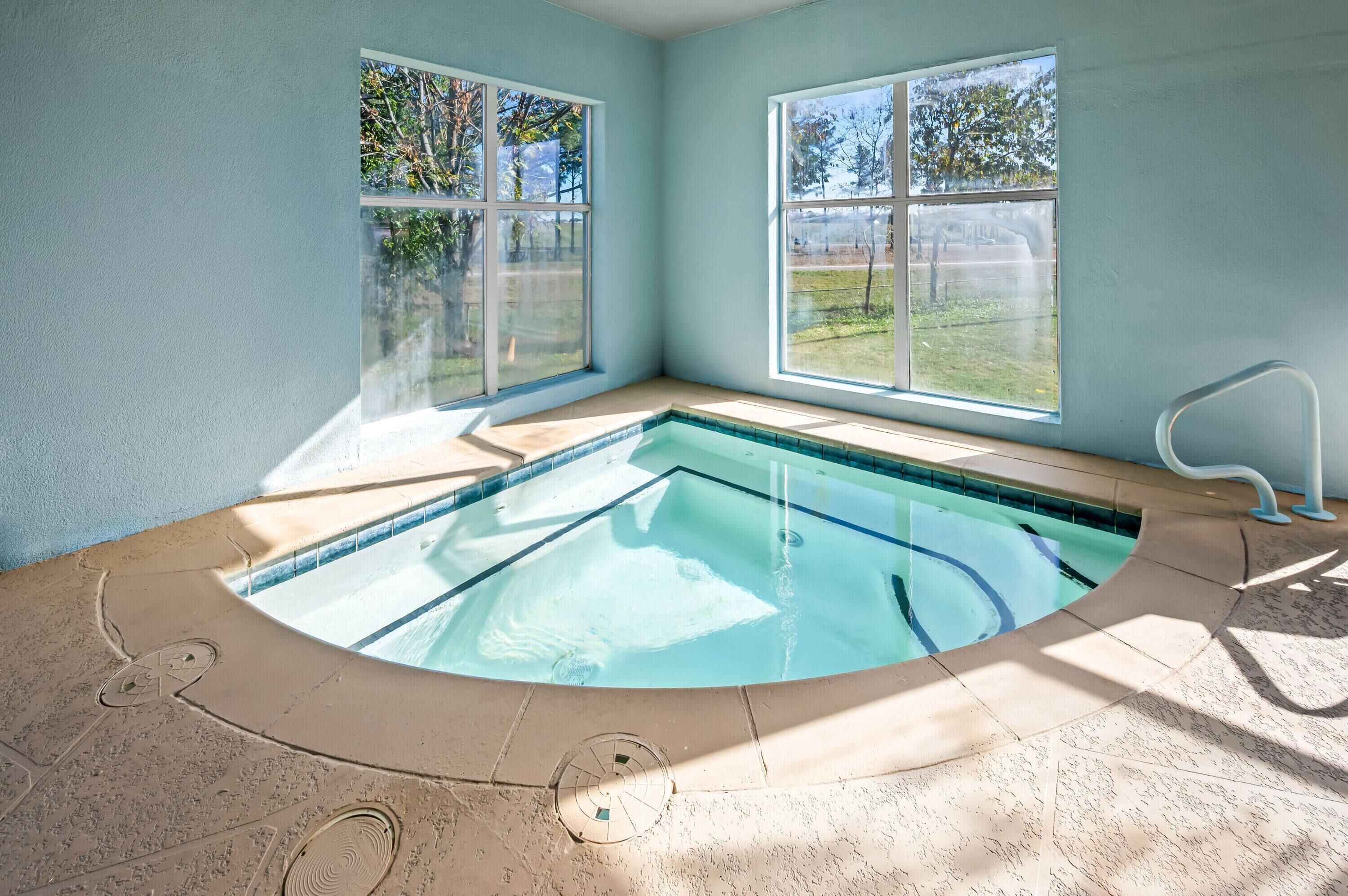 A corner pool with clear water, surrounded by light blue walls and large windows.