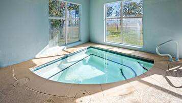A corner pool with clear water, surrounded by light blue walls and large windows.