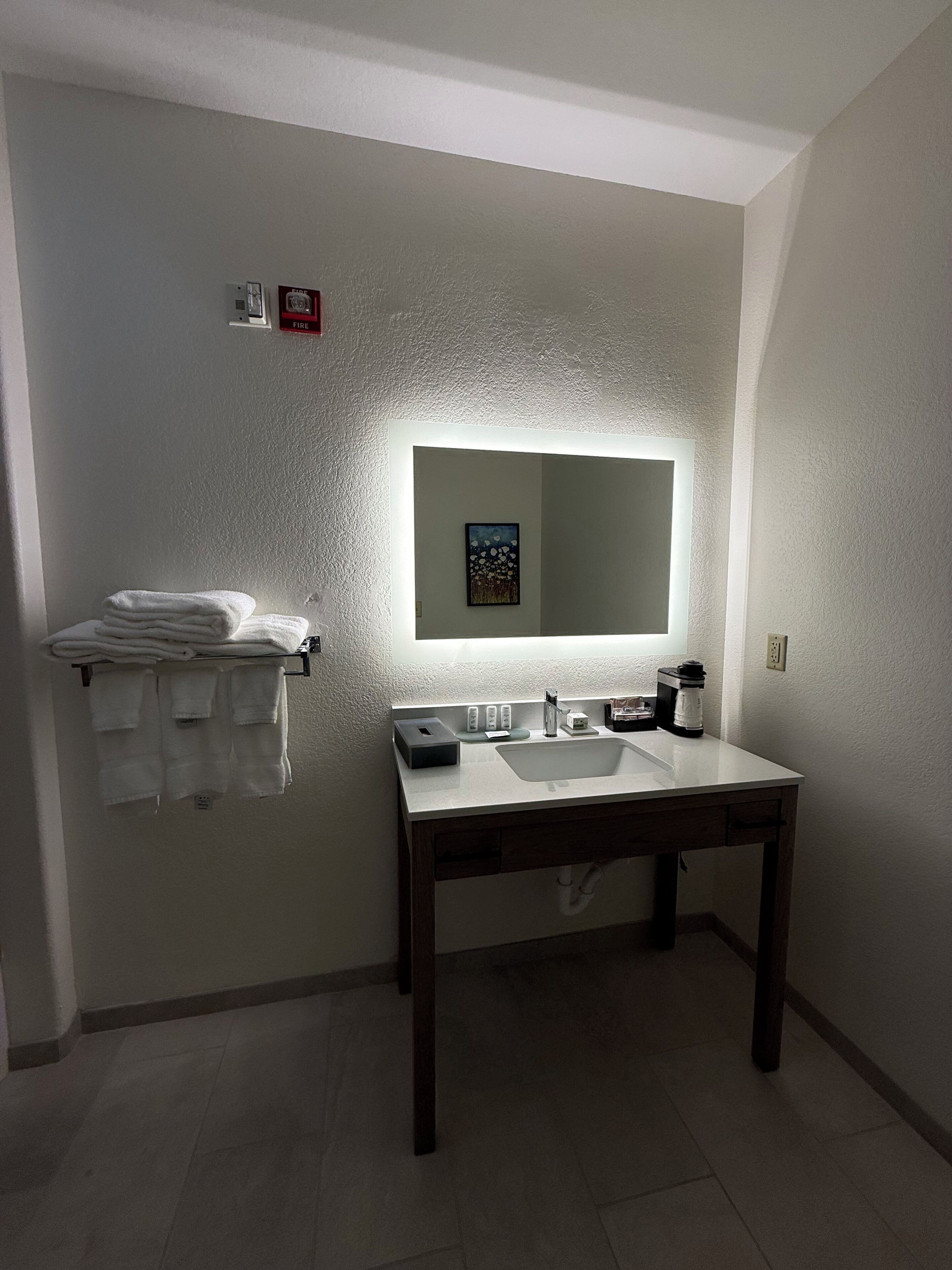 A bathroom with a white sink, a mirror, and a towel rack with folded towels.
