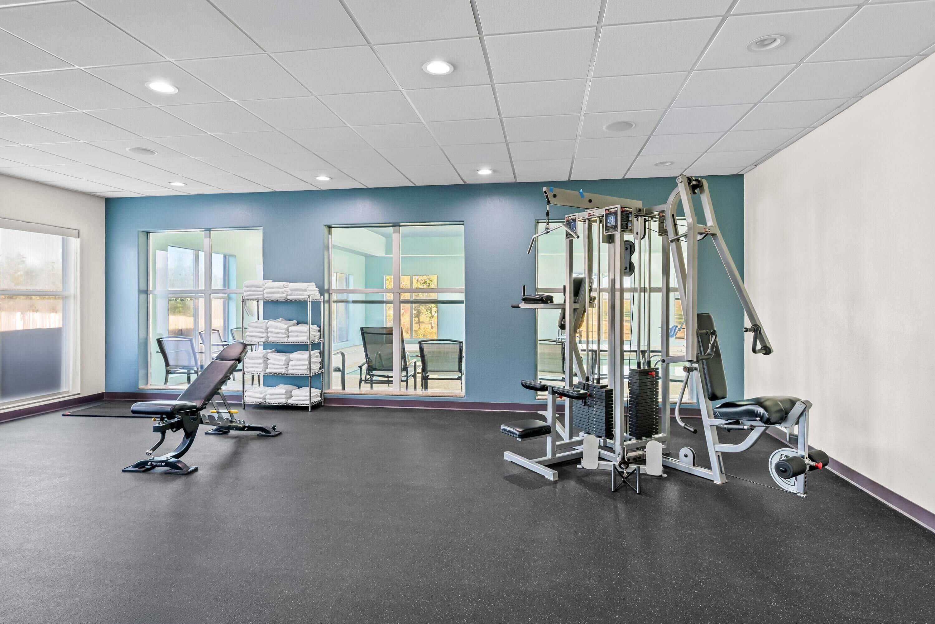 Un gimnasio con equipo de ejercicio, ventanas amplias y vistas al exterior.