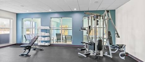 Un gimnasio con equipo de ejercicio, ventanas amplias y vistas al exterior.