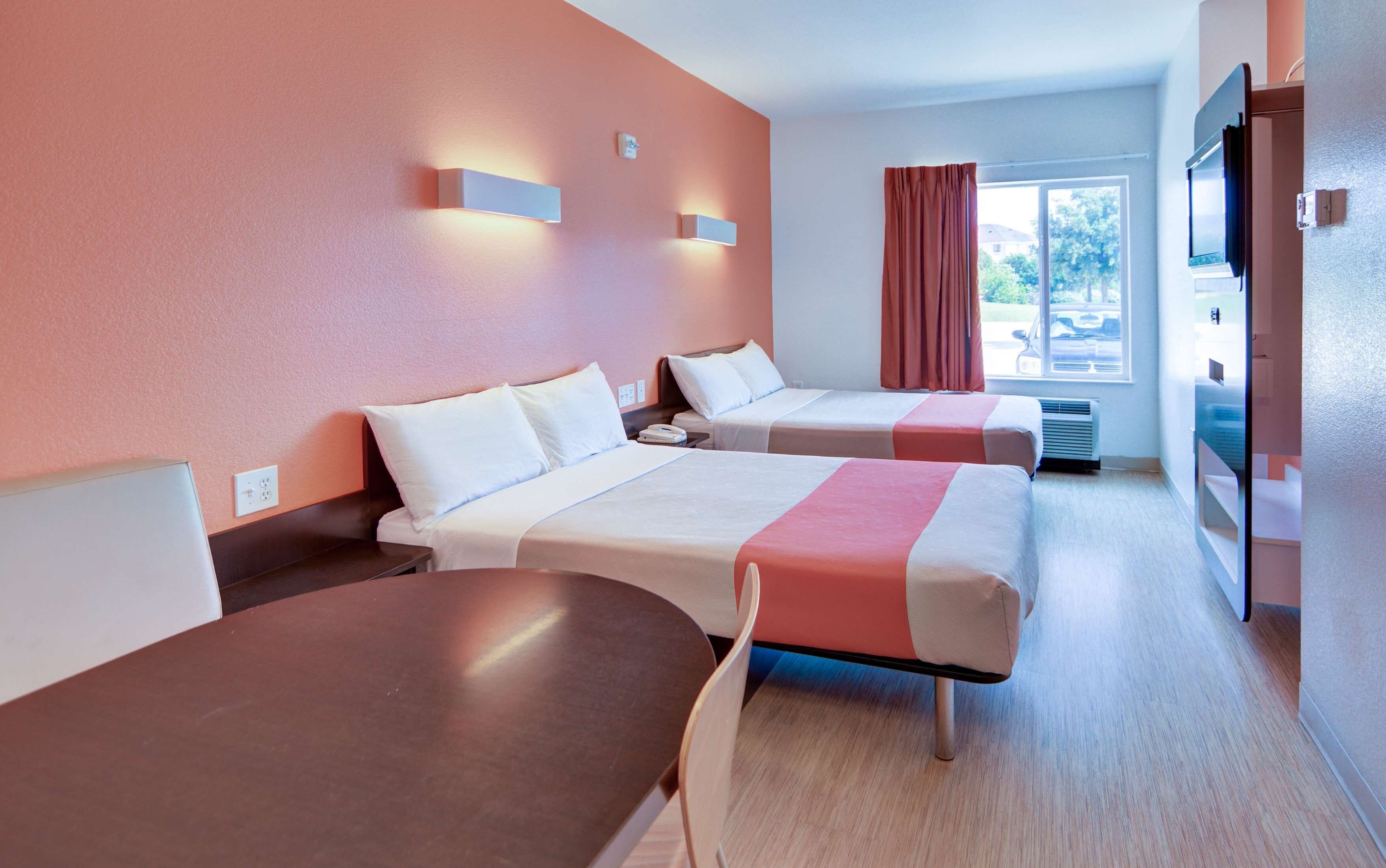 Une chambre d’hôtel avec deux lits, un bureau et une télévision.
