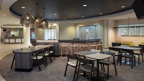 Ein modernes Restaurant mit geschwungener Gestaltung, Holztischen und -stühlen, einer Bar und einem Empfangsbereich.