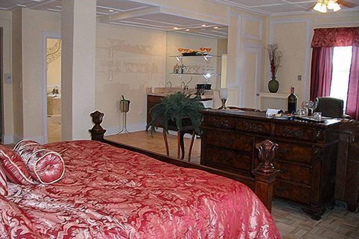 Une chambre à coucher avec un grand lit, une commode en bois, un bureau et une chaise.