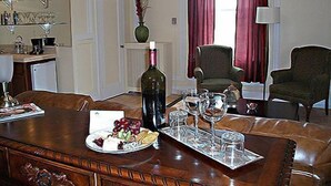 A dining area with a wooden table set for two, a bottle of wine, and a tray with glasses and a plate of food. - The George Washington Hotel (Washington)