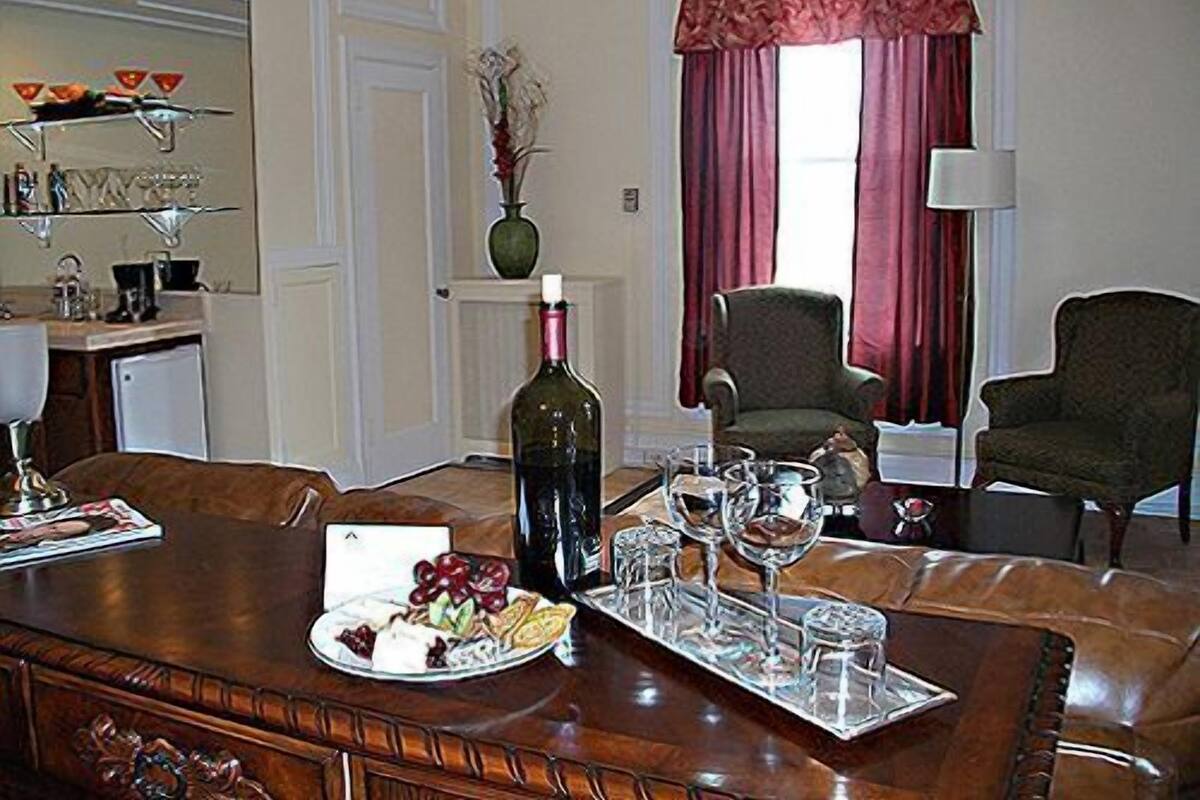 Un coin repas avec une table en bois mise pour deux personnes, une bouteille de vin et un plateau contenant des verres et une assiette de nourriture.