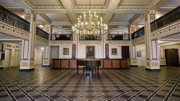 A grand hall with a patterned floor, a central chandelier, and classical architectural details. - The George Washington Hotel (Washington)
