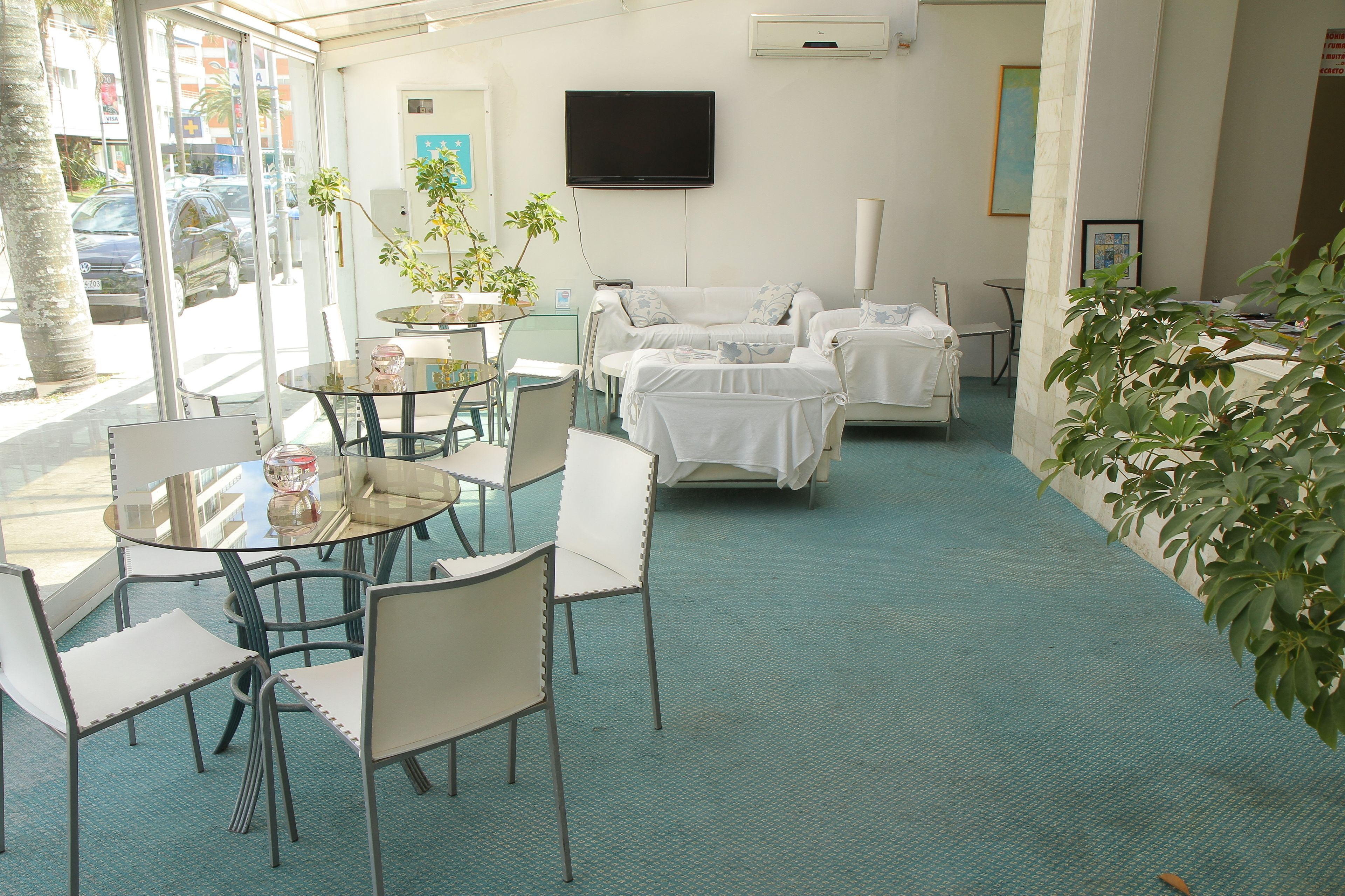 Quarto de hotel com uma janela grande, televisão de tela plana, um sofá e uma área de jantar com cadeiras e mesa.