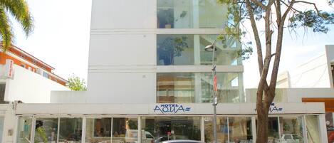 Un hotel llamado "Hotel Aqua" con una fachada moderna, ventanas amplias y una entrada visible.
