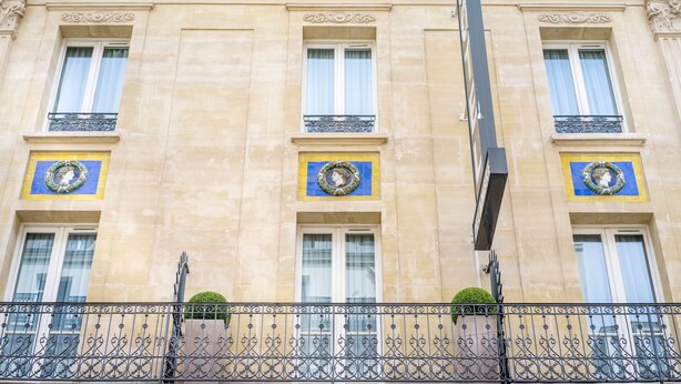 A building with three windows, each with a decorative wreath and a balcony with wrought iron railings.