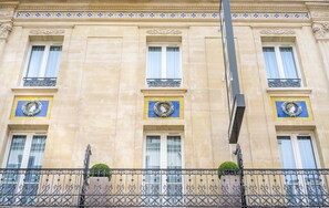 A building with three windows, each with a decorative wreath and a balcony with wrought iron railings. - Hôtel Delambre (Paris)