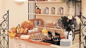 A breakfast buffet with pastries, bread, and coffee.