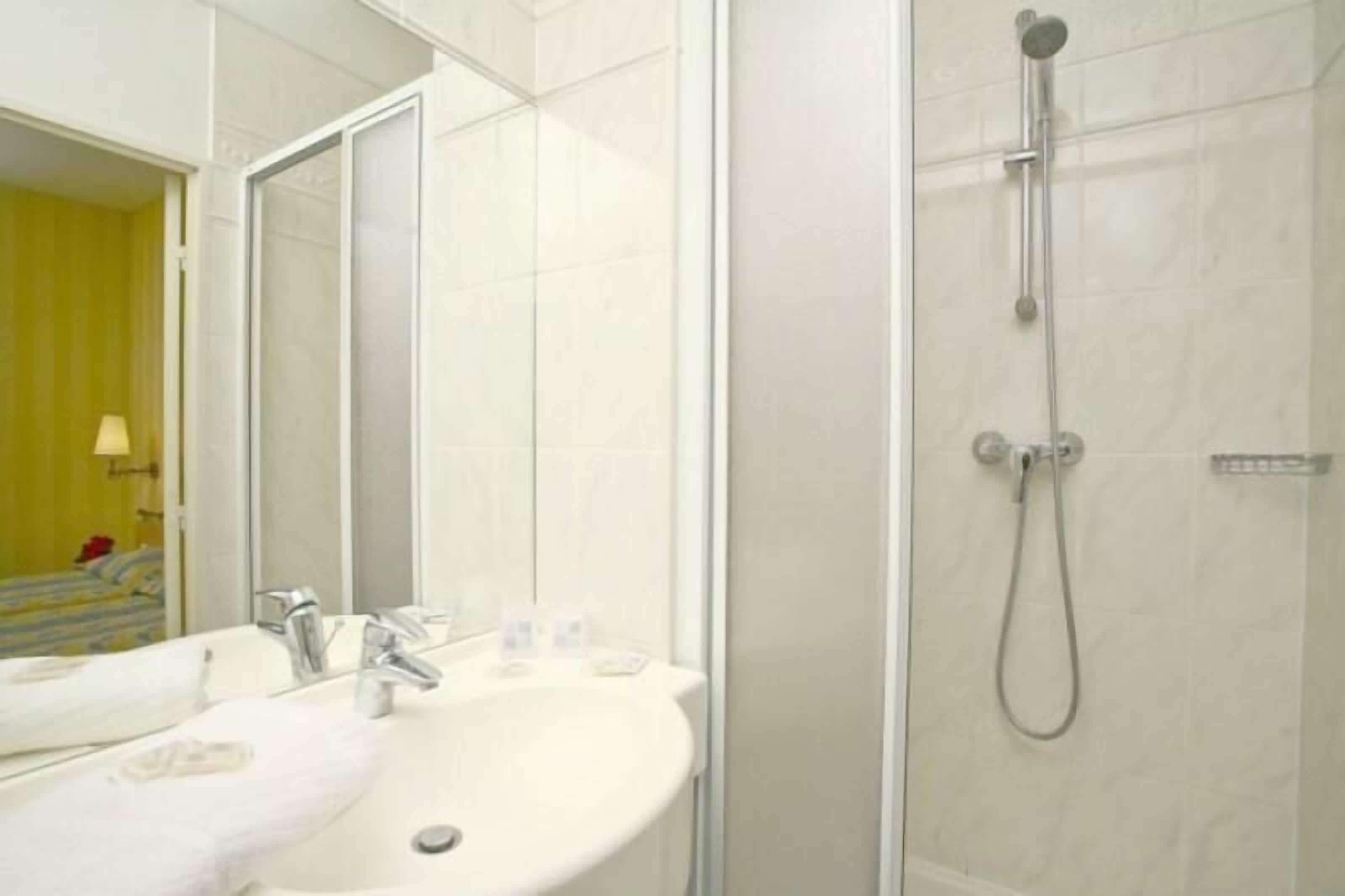 A bathroom with a sink, mirror, and shower.