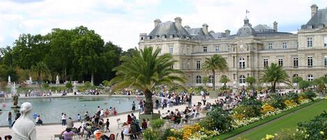 A large, historic building with a fountain and lush gardens.
