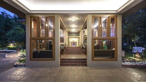 A hotel entrance with a staircase leading to the upper floor, surrounded by glass doors and windows. - Club Mahindra Thekkady (Peermade)