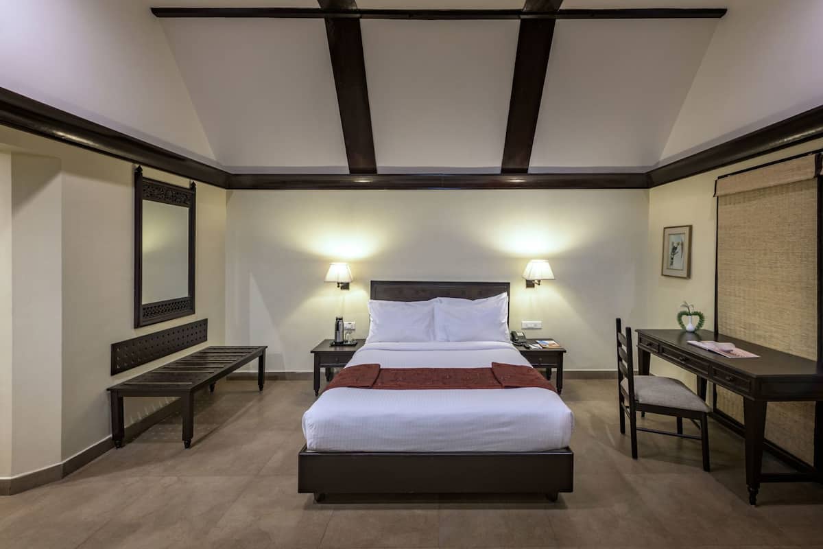 A hotel room with a large bed, bedside tables with lamps, a desk, and a chair.