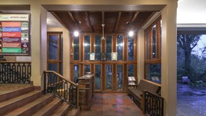 A wooden staircase leading to a covered area with a view of the outdoors, a seating area, and an activity chart on the wall. - Club Mahindra Thekkady (Peermade)