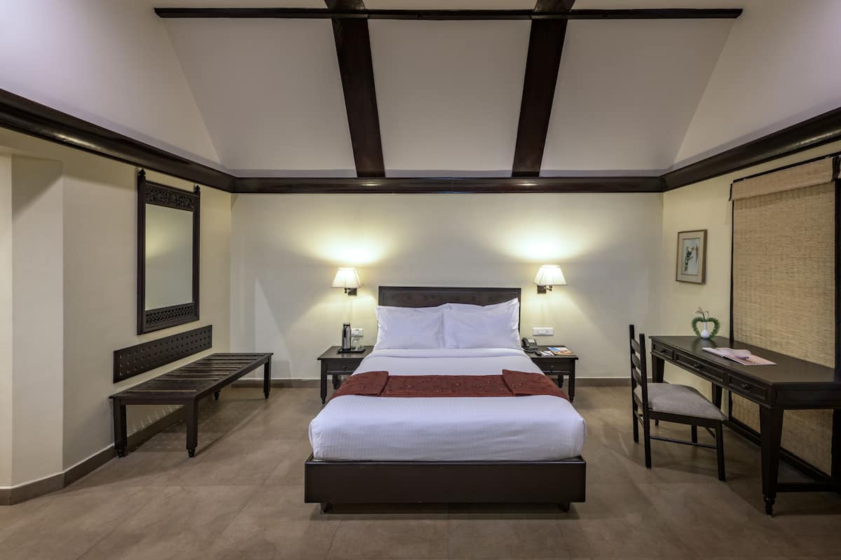 A hotel room with a large bed, bedside tables, a desk, and a chair.
