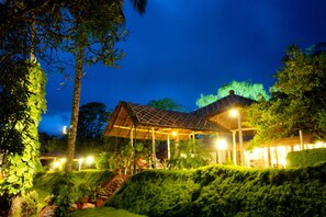 A well-lit outdoor area with a covered pavilion, surrounded by lush greenery and potted plants. - Carmelia Haven Resort (Udumbanchola)