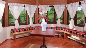 Una habitación con un rincón de madera con asientos, una mesa central y un florero con flores.