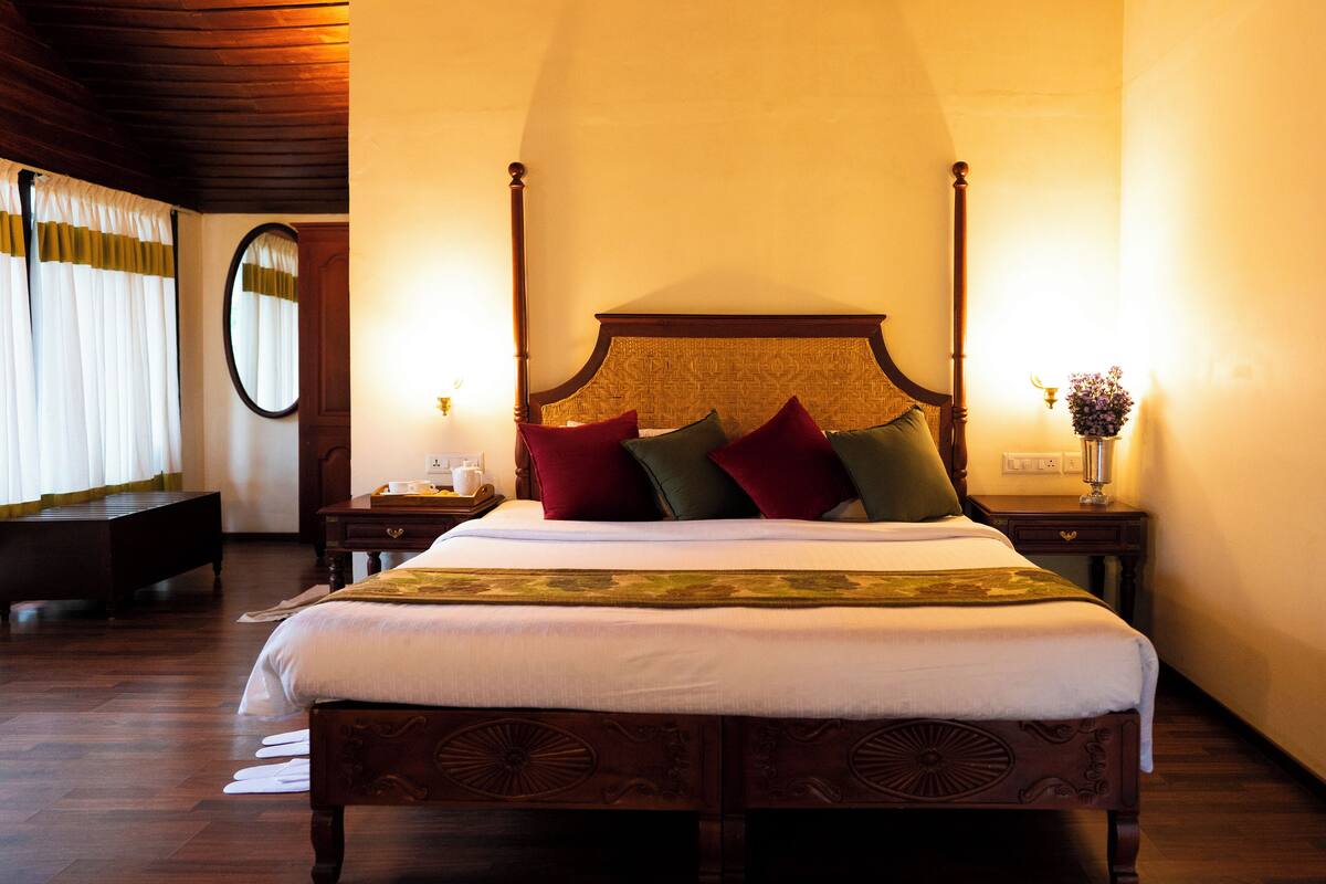 Ein Bett mit Baldachin, ein Holzkopfteil, ein Nachttisch mit Lampe und ein Spiegel an der Wand.