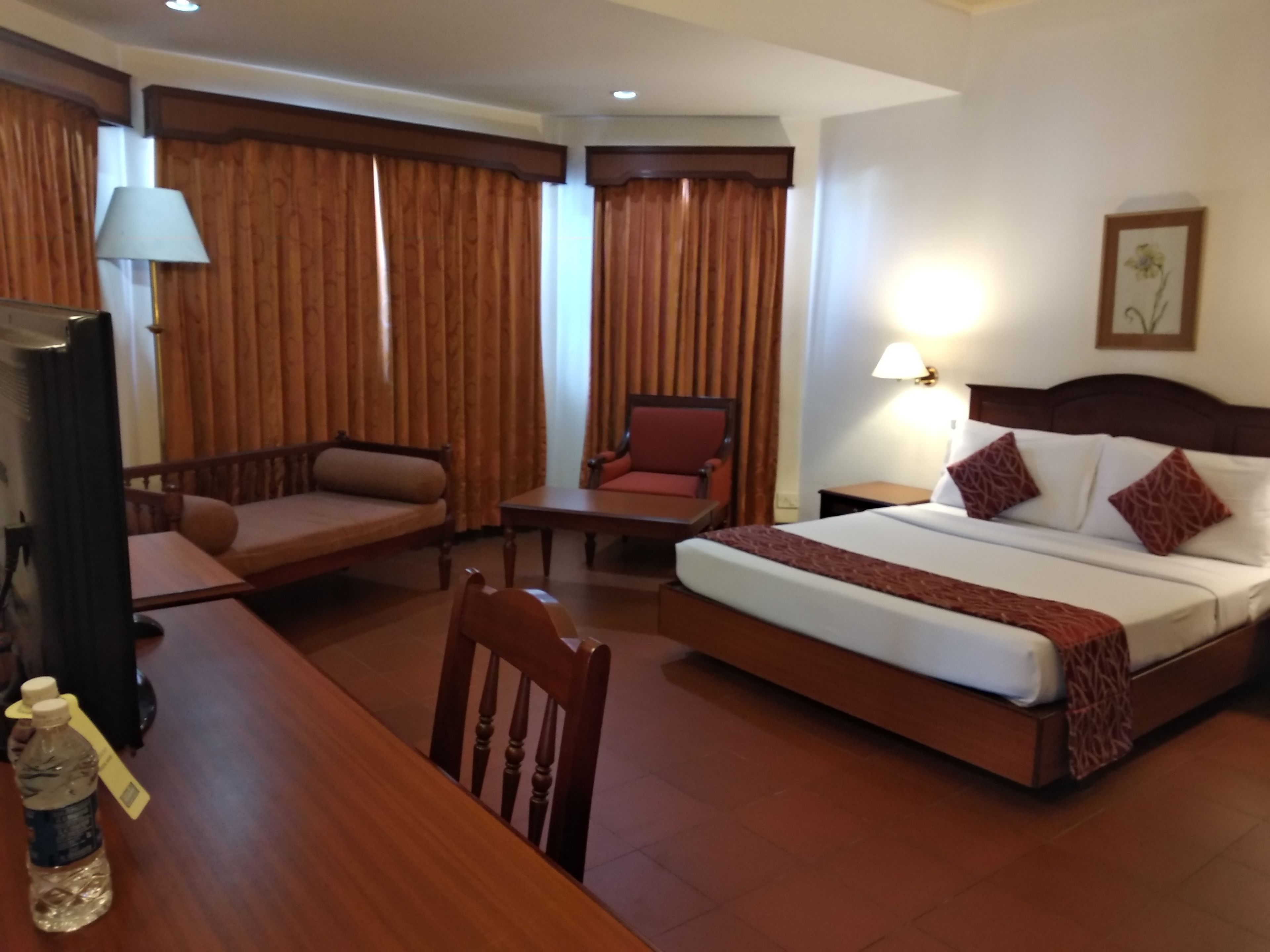 Una habitación de hotel con cama, escritorio, silla, sofá y televisor.