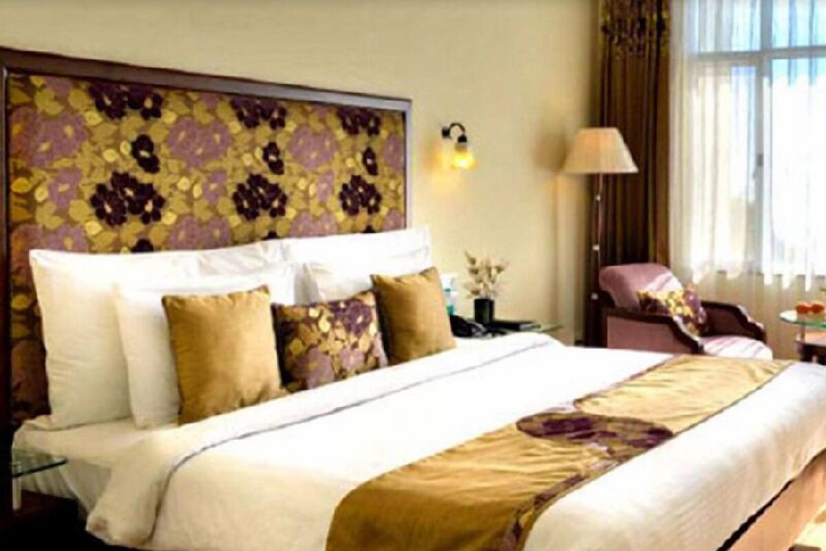 Une chambre d’hôtel avec un lit, une table de chevet, une lampe et une chaise.
