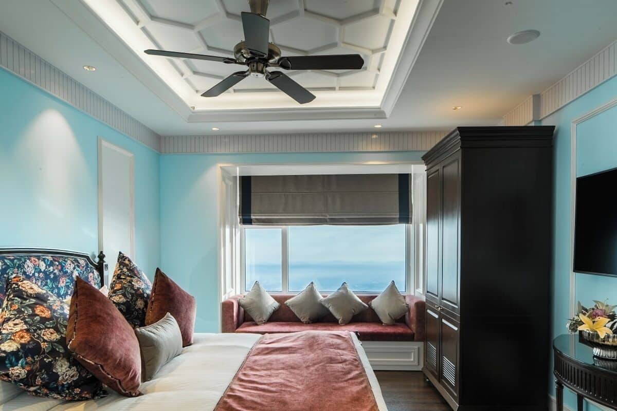 Une chambre à coucher comprenant un lit, un canapé, un ventilateur de plafond, une fenêtre avec vue et un téléviseur.