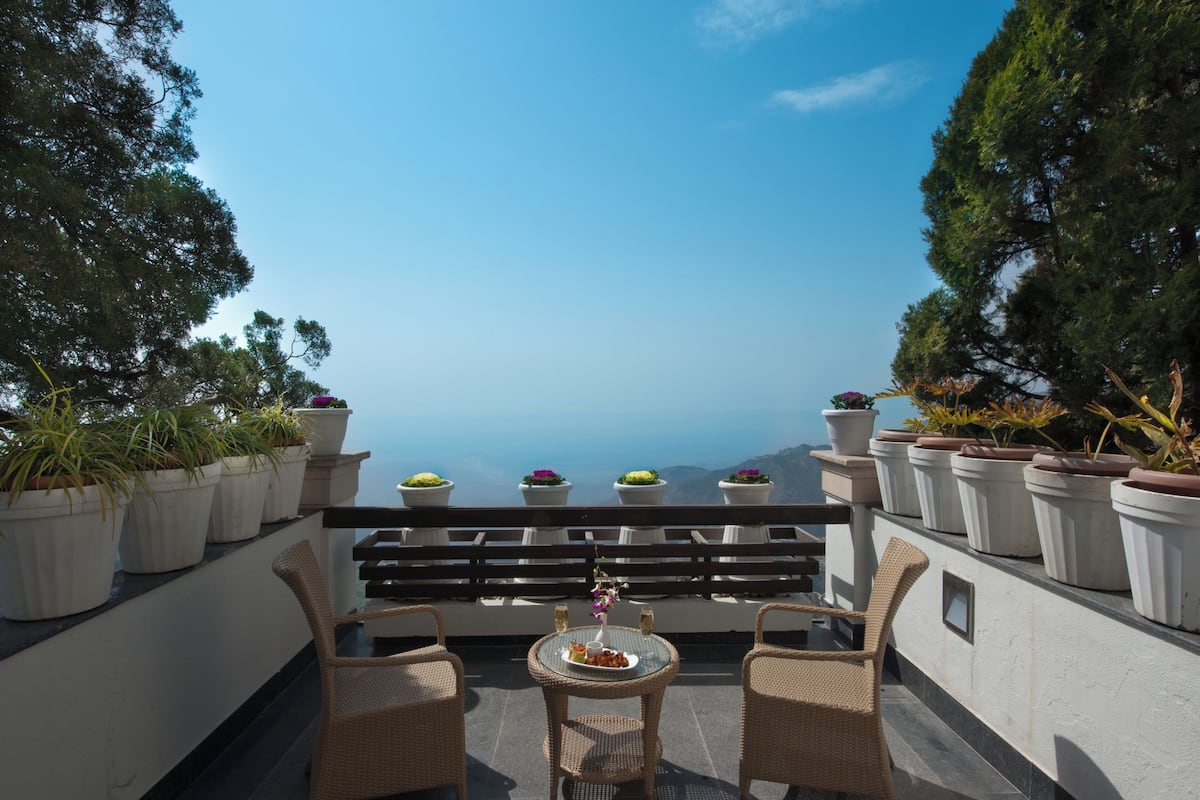 Une terrasse avec des chaises en osier, une table sur laquelle se trouve une assiette de nourriture et des plantes en pot.